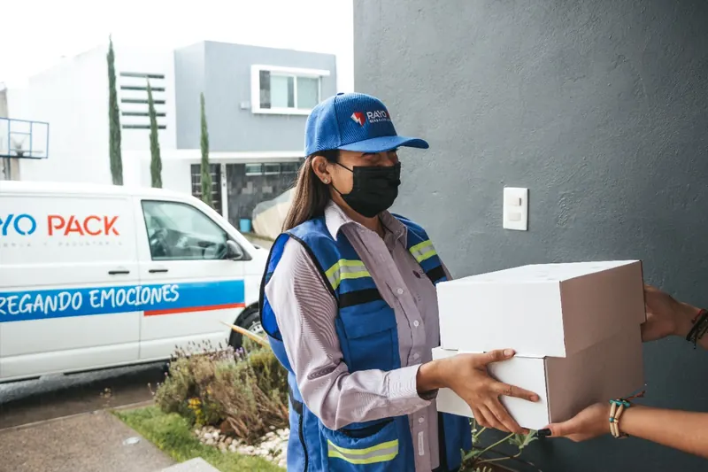 Repartidora de Rayo Pack entregando dos cajas en la puerta de una casa